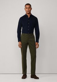 Marineblauw overhemd met lange mouwen, gecombineerd met olijfgroene broek en bruine geklede schoenen; gladde textuur, slim-fit.