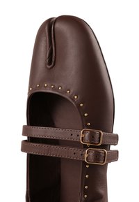 Chaussure en cuir marron style Tabi avec un orteil fendu, deux brides à boucle et des clous dorés autour de l'ouverture.