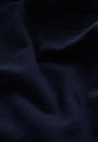 Sötétkék, kötött pulóver sima textúrával, magas bordázott gallérral és puha anyaggal, amely finoman simul.