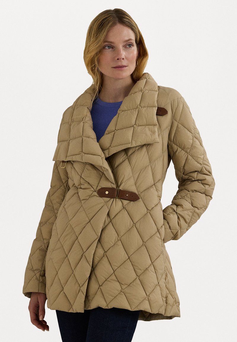 Casaco bege acolchoado com um colarinho largo, fecho de pressão e detalhes em couro. Apresenta um ajuste solto e um padrão de costura diagonal.