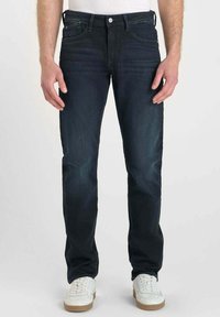 Jean en denim bleu foncé avec une coupe droite, dotés de cinq poches, d'un surfilage contrastant et d'une légère décoloration sur l'ensemble du tissu.