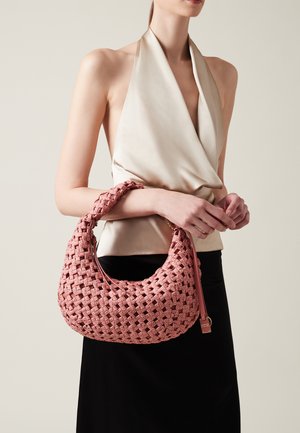 Geflochtene rosa Handtasche in runder Form, mit einer strukturierten Oberfläche und einem einzelnen Riemen. Das Material scheint aus Leder oder einem ähnlichen synthetischen Stoff zu bestehen.