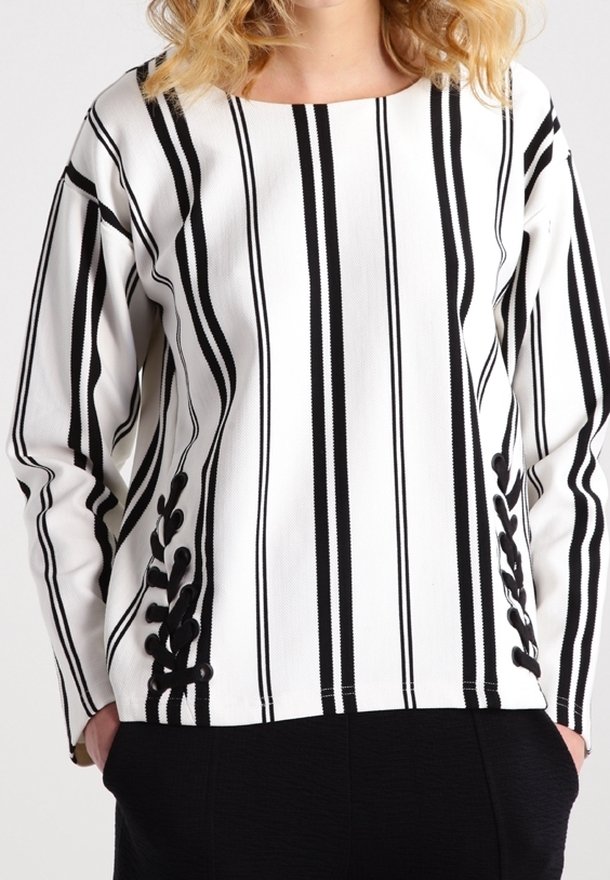 Vit långärmad topp med svarta vertikala ränder och blommiga detaljer. Texturerat tyg, rund halsringning och lös passform med sidodetaljer.