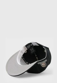 Musta lakki, jossa on kaareva harmaa lippa, etuosassa logo ja sisällä tarrat. Sujuva kangas, jossa on kontrastivärejä ja ompeluyksityiskohtia.