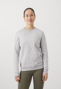 Lys grå genser med lange ermer og rund hals. Har ribbede mansjetter og kant, liten logo detalj på brystet, og teksturert stoff.