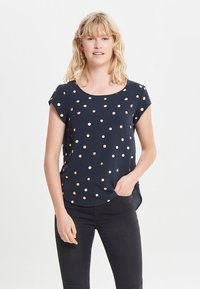Mørkeblå kortærmet top med guldprikker, rund halsudskæring og en afslappet pasform. Glat stof med en let skinnende overflade og en buet kant.