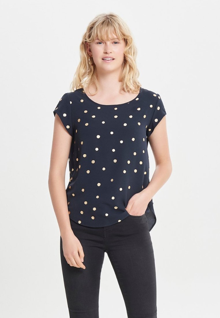Mørkeblå kortærmet top med guldprikker, rund halsudskæring og en afslappet pasform. Glat stof med en let skinnende overflade og en buet kant.