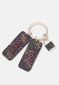 Porte-clés en cuir avec deux étiquettes ; l'une en brun foncé avec "GUESS" en rouge, l'autre en brun foncé avec "1981". Quincaillerie et accents métalliques inclus.