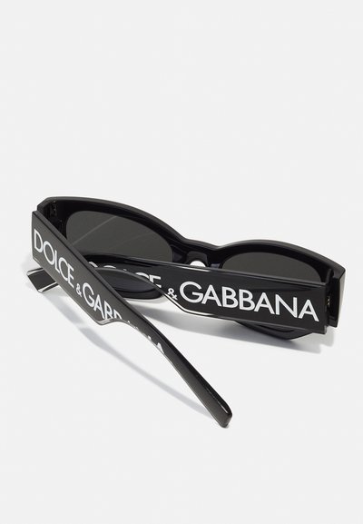 Occhiali da sole neri con un design audace e angolare. Caratterizzati da montature spesse con il marchio bianco "DOLCE & GABBANA" e lenti scure.