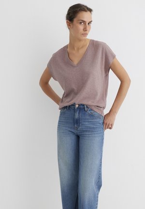 Helles mauve V-Ausschnitt-T-Shirt mit kurzen Ärmeln, kombiniert mit hoch taillierten, hellblauen, weiten Jeans. Weicher Stoff; lässiges Design.