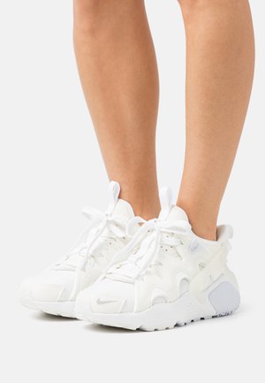 Witte sportieve schoenen met een gestructureerde bovenkant, mesh-panelen en ergonomische zolen. Bevat opvallende veters en een grijze accent bij de hiel.