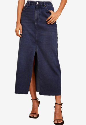 Mørkeblå denim midinederdel med slids foran i midten, høj talje og rå kant, båret med sorte sandaler med stropper og hæl.
