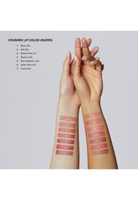 Próbki siedmiu odcieni pomadek na dwóch ramionach, prezentujące odcienie nude w różnych teksturach, w tym matowych i błyszczących. Etykiety załączone.