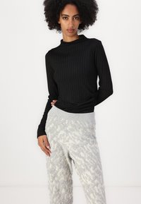 Black ribbed long-sleeve top paired with light gray patterned knit pants featuring a soft texture and elastic waistband.