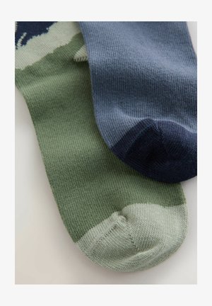Deux paires de chaussettes : une en vert discret avec un bout de pied vert clair, l'autre en bleu avec un bout de pied bleu foncé. Texture tricotée, nuances variées.