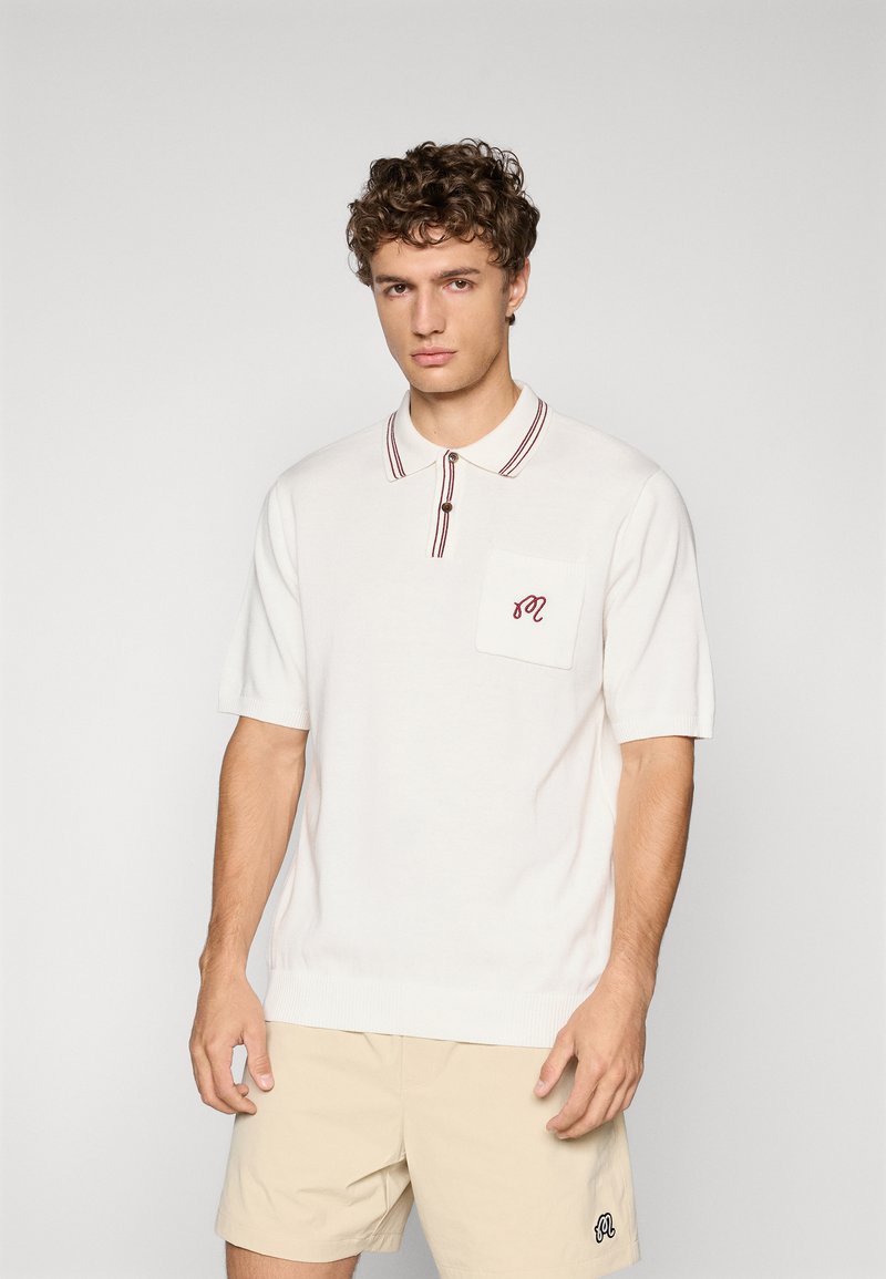 Hvit polo-skjorte med korte ermer, med krage i burgunderstriper, en brystlomme og et brodert logo. Glatt tekstur.