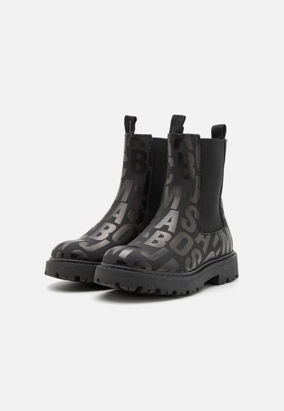 Sorte chelsea støvler med en glatt overflate som har et matt mønster av store bokstaver, elastiske sidepaneler og robuste gummisåler.
