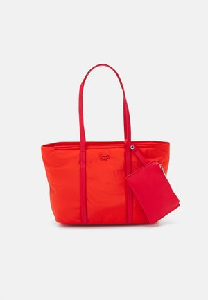 Czerwona torba typu tote z długimi uchwytami i przymocowaną małą dopasowaną saszetką na zamek, minimalistyczny design, miękka faktura tkaniny.