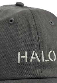 Eine Nahaufnahme einer dunkelgrauen Kappe mit dem gestickten Text "HALO" in hellgrau auf der Vorderseite.