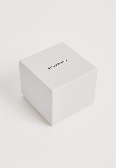 Boîte blanche en forme de cube avec l'inscription « Completedworks » imprimée en noir, centrée sur la surface supérieure, sur un fond blanc uni.