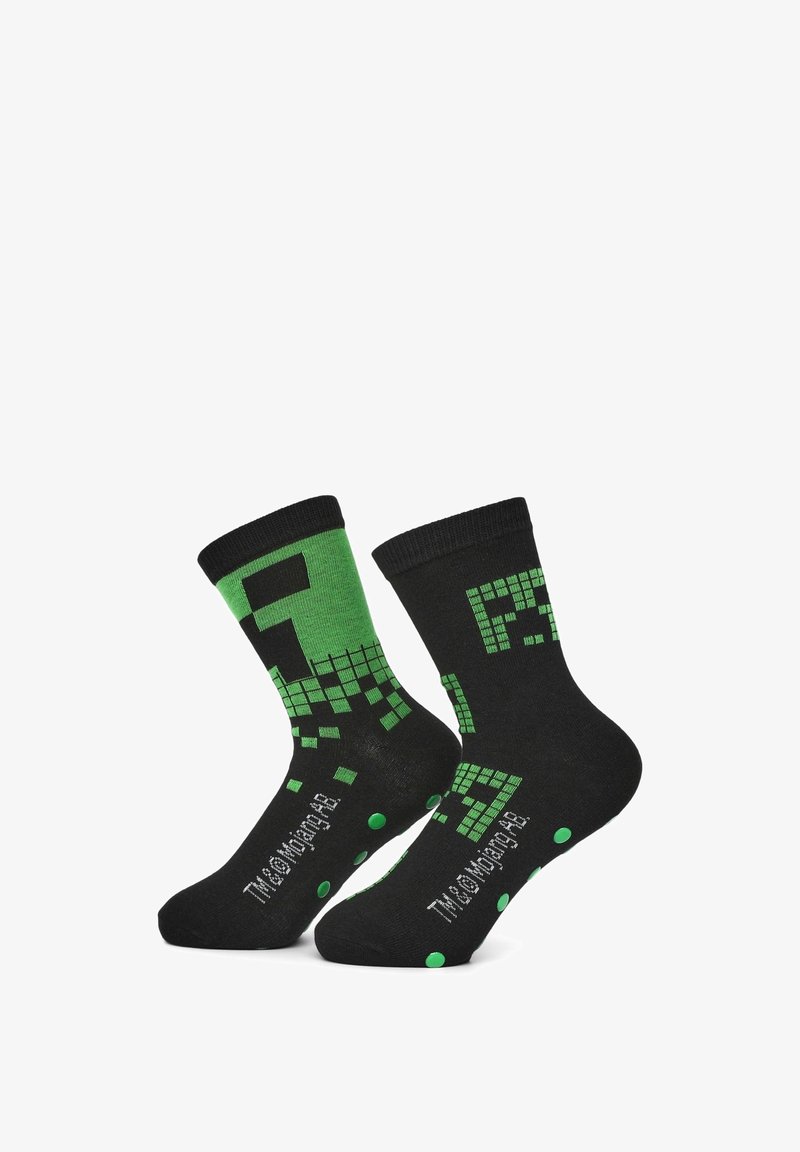 Czarne skarpetki z zielonymi pikselowymi grafikami, wzmocnioną mankietą, kropkowanymi akcentami na podeszwie oraz logo po boku.