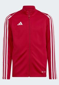 Rote Zip-Jacke aus leichtem Material mit weißen Streifen entlang der Ärmel und einem Logo auf der Brust. Der Stoff wirkt glatt und leicht.