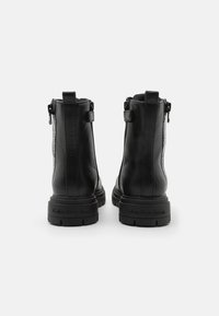 Black leather ankle boots with a textured finish, side zippers, and a chunky rubber sole. Features branding on the sole and side.