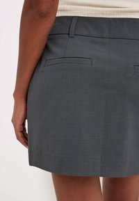 Harmaa räätälöity mini-hame, jossa on sileä texture, kaksi takataskua ja suora leikkaus, sekä siisti helma.