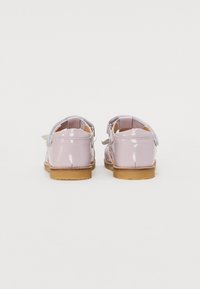Chaussures en cuir verni lavender brillant avec une semelle en caoutchouc beige, dotées d'une sangle arrière pour un maintien sécurisé et d'une couture délicate.