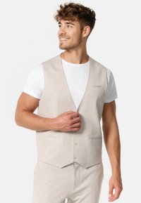 Chaleco gris claro hecho de una tela suave, con un diseño de cuello en V, dos bolsillos en la parte delantera y un cierre con botones en el frente.