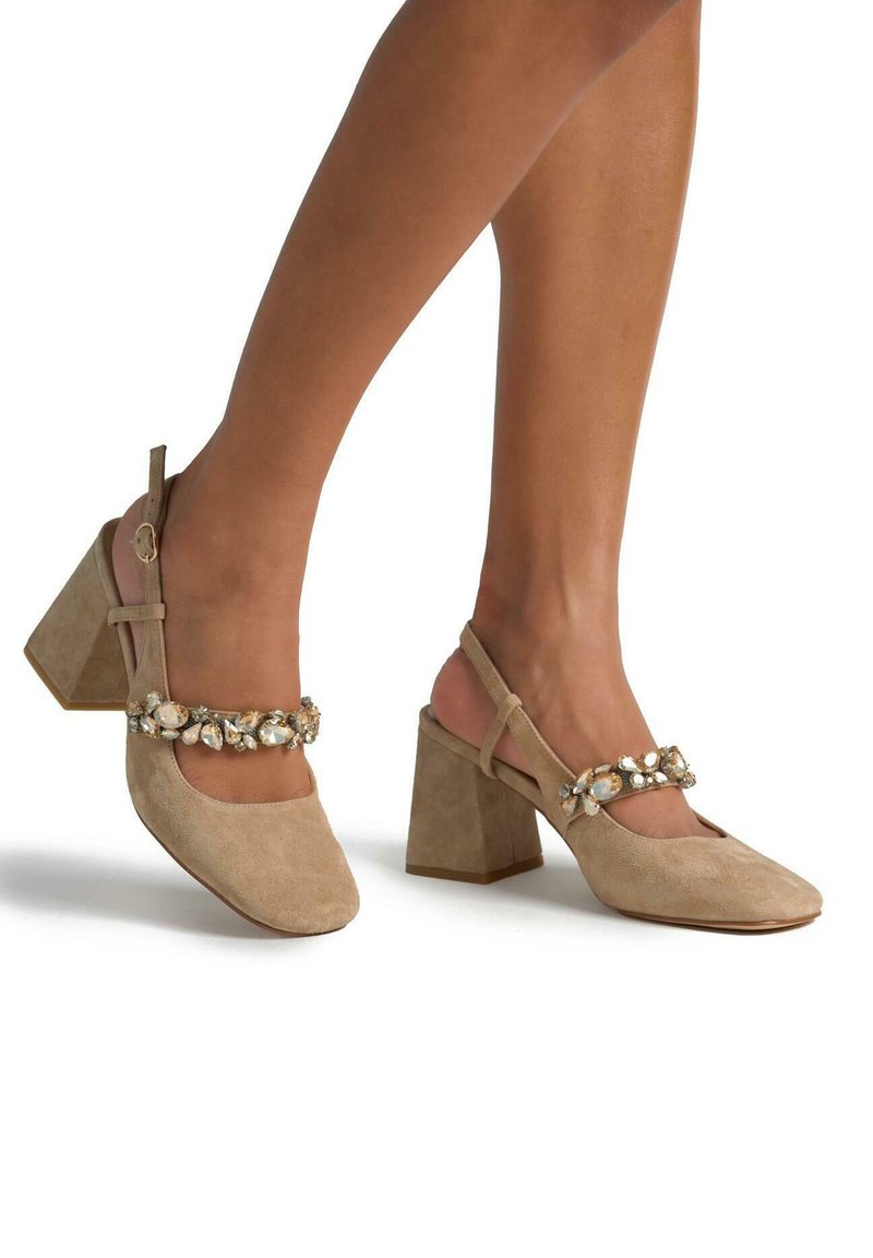 Scarpe con tacco a blocco in suede beige, con punta quadrata, caratterizzate da una fascia decorativa impreziosita da gemme trasparenti e un design con slingback regolabile.