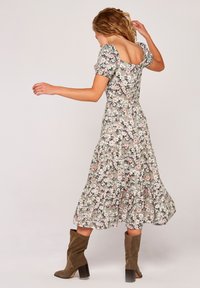 Kwiatowa sukienka midi w kolorze zielonym z bufkami i kwadratowym dekoltem z tyłu. Posiada warstwową spódnicę oraz skomplikowany wzór kwiatowy z różowymi i białymi akcentami.