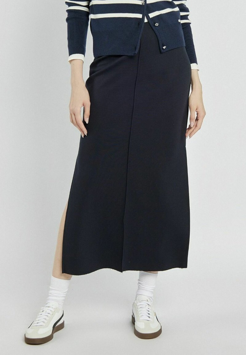 Granatowa, sięgająca kostek spódnica z bocznym rozcięciem. Gładka, elastyczna tkanina o prostym fasonie. W zestawieniu z białymi trampeczkami i skarpetkami.