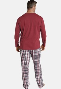 Red long-sleeve shirt paired with checkered pajama pants in shades of navy, white, and burgundy, featuring an elastic waistband.