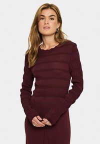 Burgundy ribbed knit dress with long sleeves; features scalloped neckline and textured detailing along sleeves and waist.