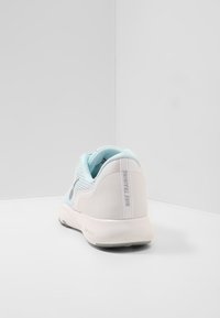 Jasnoniebieskie siateczkowe buty treningowe z białą gumową podeszwą, z szarym logo Nike i napisem "Nike Training" na tylnej części obcasa.