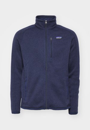 Marineblaue Fleecejacke mit hohem Kragen, durchgehendem Reißverschluss, seitlichen Taschen und einer Brusttasche mit dem Patagonia-Logo.