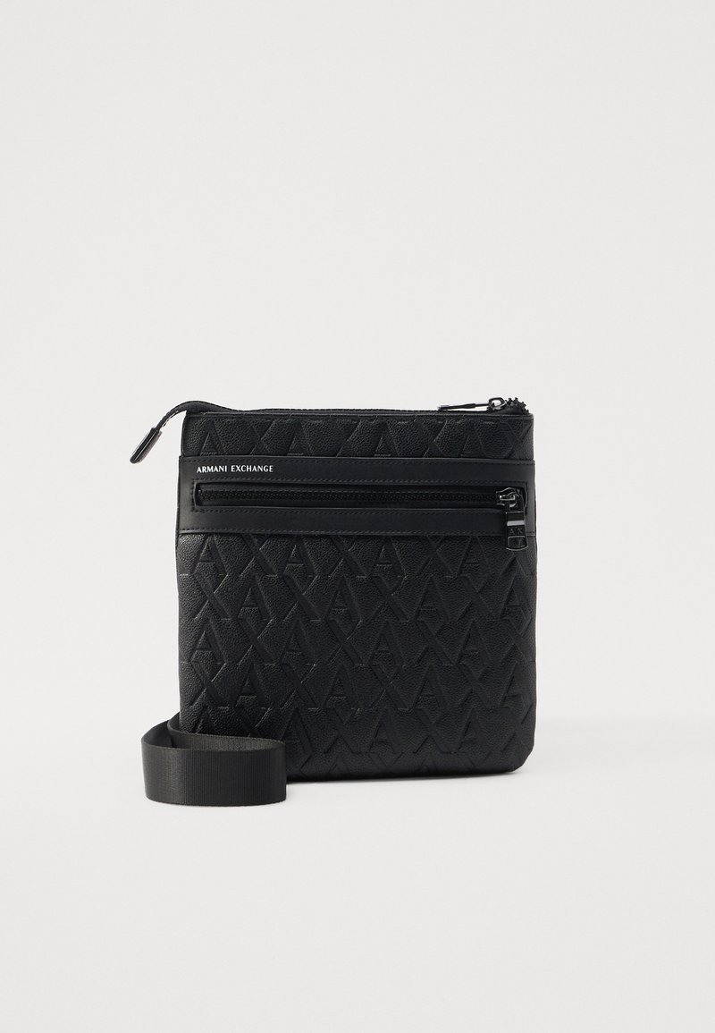 Sac bandoulière en nylon noir avec logo embossé, poche zippée et sangle réglable. Présente une surface texturée et un design minimaliste.