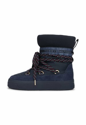 Stivali invernali blu navale con risvolto in maglia, tomaia in suede e sintetico, lacci decorati e occhielli metallici. Presentano una suola in gomma piatta.