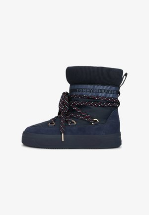 Stivali invernali blu navale con risvolto in maglia, tomaia in suede e sintetico, lacci decorati e occhielli metallici. Presentano una suola in gomma piatta.