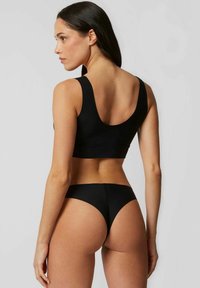 Braletă neagră cu bretele late și spate adânc, asortată cu chiloți negri din bikini. Ambele sunt fabricate dintr-un material neted și elastic.