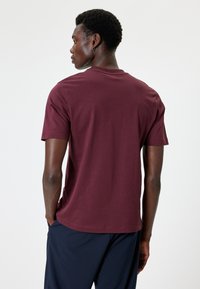 T-shirt bordeaux a maniche corte con scollo rotondo, realizzato in morbido tessuto di cotone, con un design semplice e una vestibilità comoda.