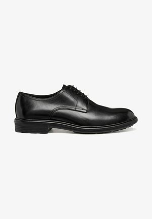 Chaussure habillée pour homme en cuir noir poli avec fermeture à lacets et talon bas empilé, vue de profil sur fond blanc.