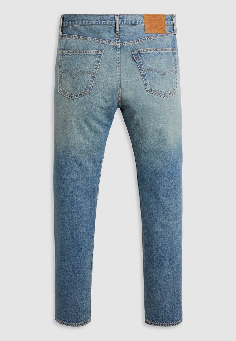 Jean en denim bleu clair avec une jambe droite, présentant deux poches arrière et une patch en cuir marron à la taille avec le logo de la marque.