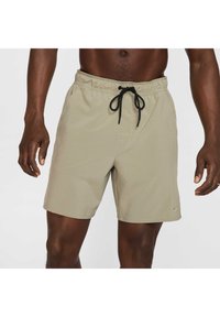 Bañador beige hecho de una tela ligera, con cintura elástica, cordón negro, bolsillos laterales y un pequeño logo en el dobladillo.