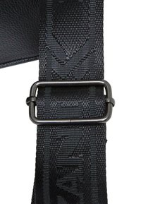 Crni najlonski remen s teksturama, s metalnom kopčom za podešavanje. Bliski prikaz ističe izdržljivost i dizajn remena.