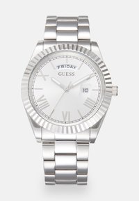 Sudraba nerūsējošā tērauda pulksteņi ar rievojumu zīmogu, balta sejas plāksne, romiešu ciparu atzīmes, datuma rādītājs un savienota metāla aproce.