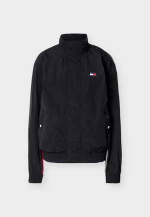 Juoda lengva striukė su stovinčiu apykakliu, elastiniais rankogaliais ir apačia, šoninėmis kišenėmis su spaudėmis ir mažu Tommy Hilfiger logotipu ant krūtinės.