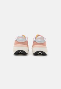 Scarpe da corsa Saucony con una combinazione di colori rosa e crema, tomaia in suede e rete testurizzata, colletto imbottito e suola in gomma nera.