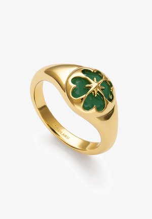 Anillo de oro con diseño de trébol de cuatro hojas verde en la parte superior, banda lisa y nombre de marca grabado en el interior.
